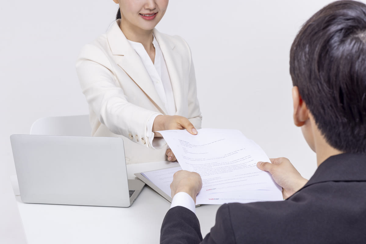 담당자가 완성된 번역공증 서류를 의뢰인에게 건네며 인증까지 마친 결과물을 전달하는 모습